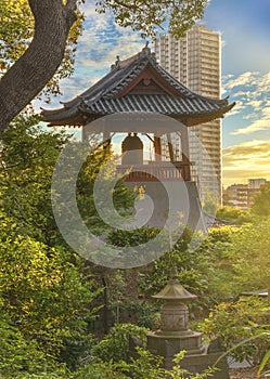 Sunset on the buddhist Time Bell of Kaneiji Temple in Ueno Park with skyscraper in background. photo